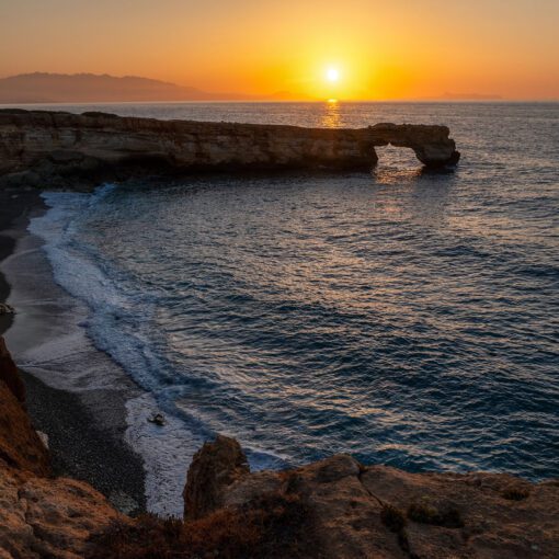 Západ slnka pri Arch of Skaleta na pobreží Kréty