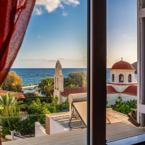 Výhľad z okna na kostol a more – Panormos, Kréta
